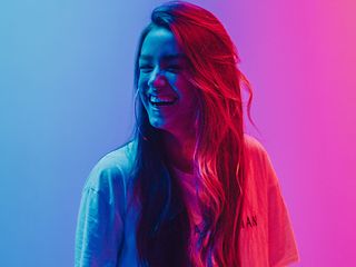 lachende Frau beleuchtet mit blau und magentafarbenen Licht