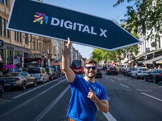 Ein Mann trägt ein Hinweisschild zur Digital X.