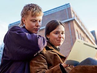 Zwei junge Leute schauen auf einen Laptop.