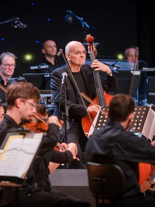 Das Bild zeigt den Jazz-Bassisten Lars Danielsson inmitten des Beethoven Orchester Bonn.