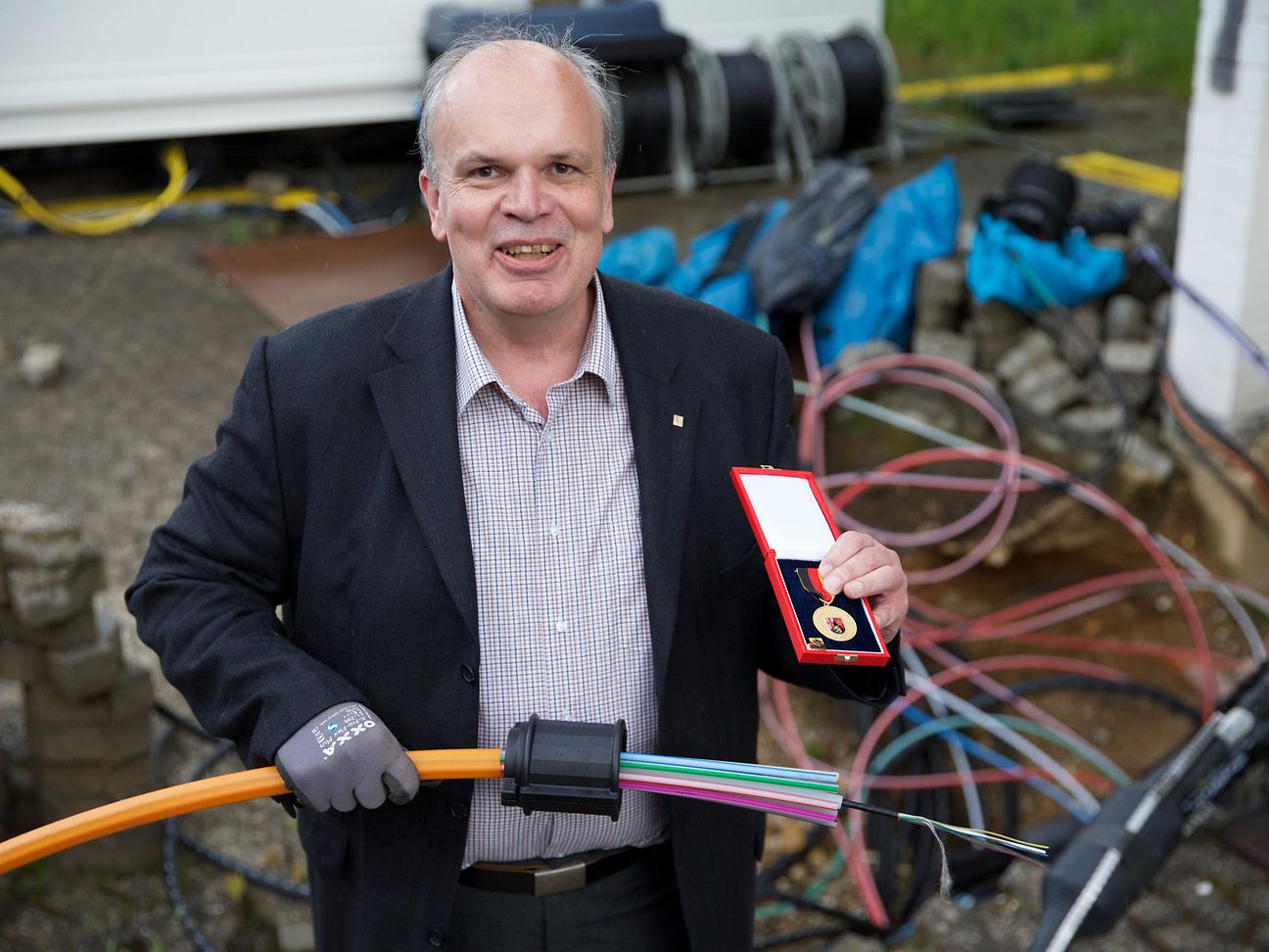 Michael Guthart hält seine Verdienstmedaille sowie ein Glasfaserbündel in der Hand
