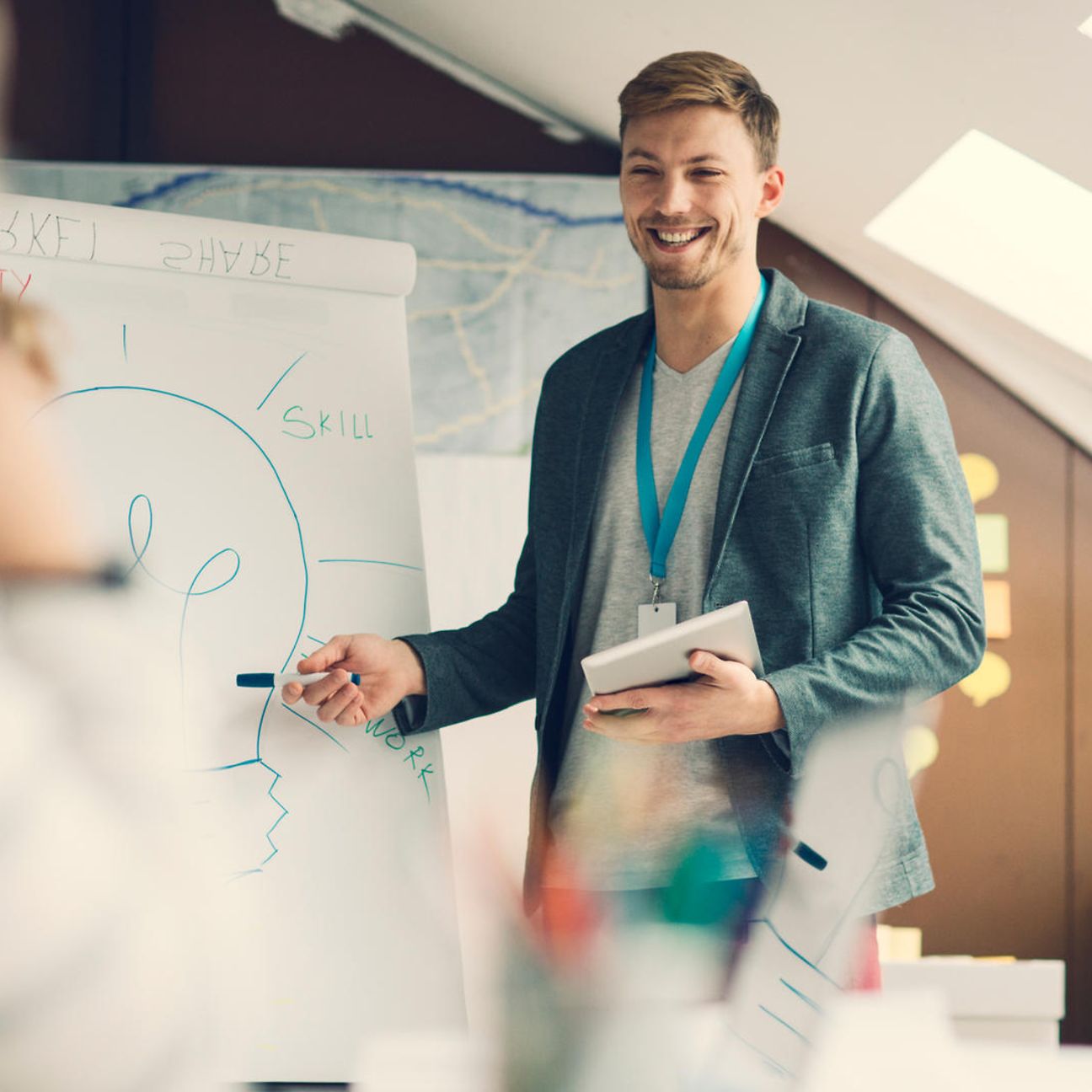 Ein junger Mann hält eine Präsentation vor einer Flipchart, auf der eine Glühbirne zu erkennen ist.