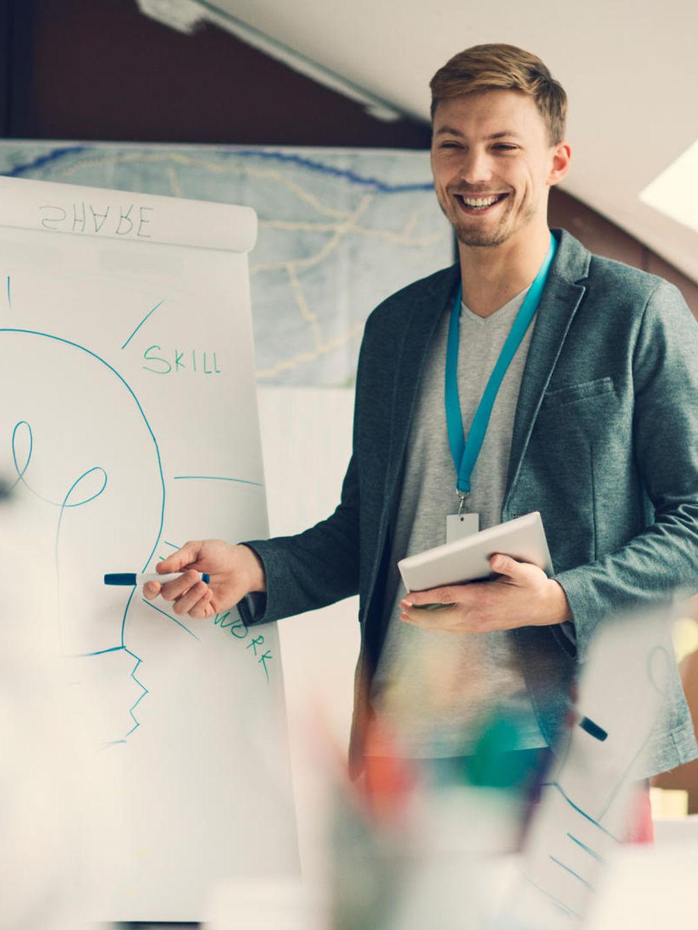 Ein junger Mann hält eine Präsentation vor einer Flipchart, auf der eine Glühbirne zu erkennen ist.
