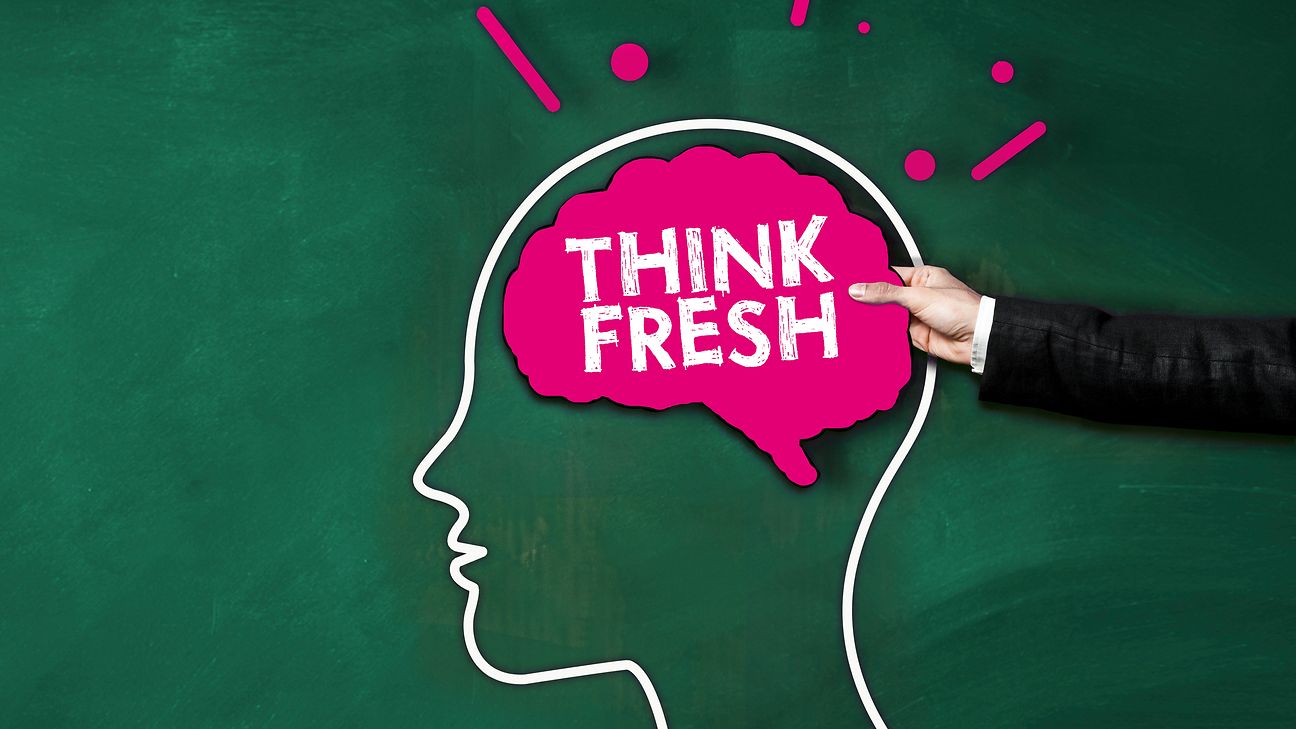 A male hand holds a sign as a brain with the inscription Think fresh.