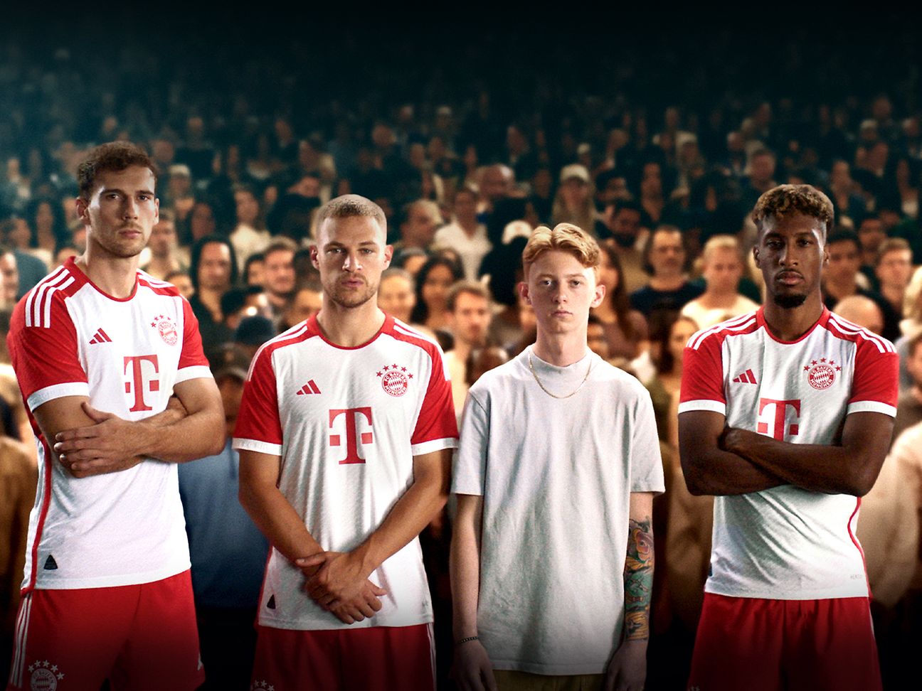 Drei Spieler des FC Bayern München und ein junger Mann stehen vor Fußballfans.