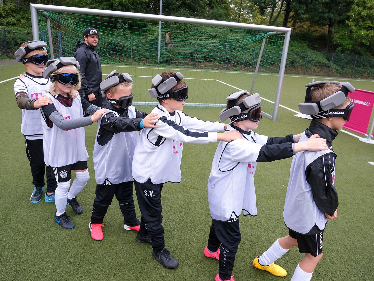Kinder mit einer Blindenbrille bilden eine Kette.