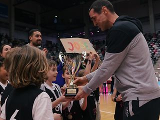 Telekom Baskets Headcoach Roel Moors bei der Übergabe des Siegerpokals an die Kinder der Josefschule.