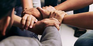 Close-up of five different hands holding each other's wrists, forming a circle