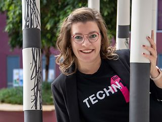 A woman with glasses smiles at the camera