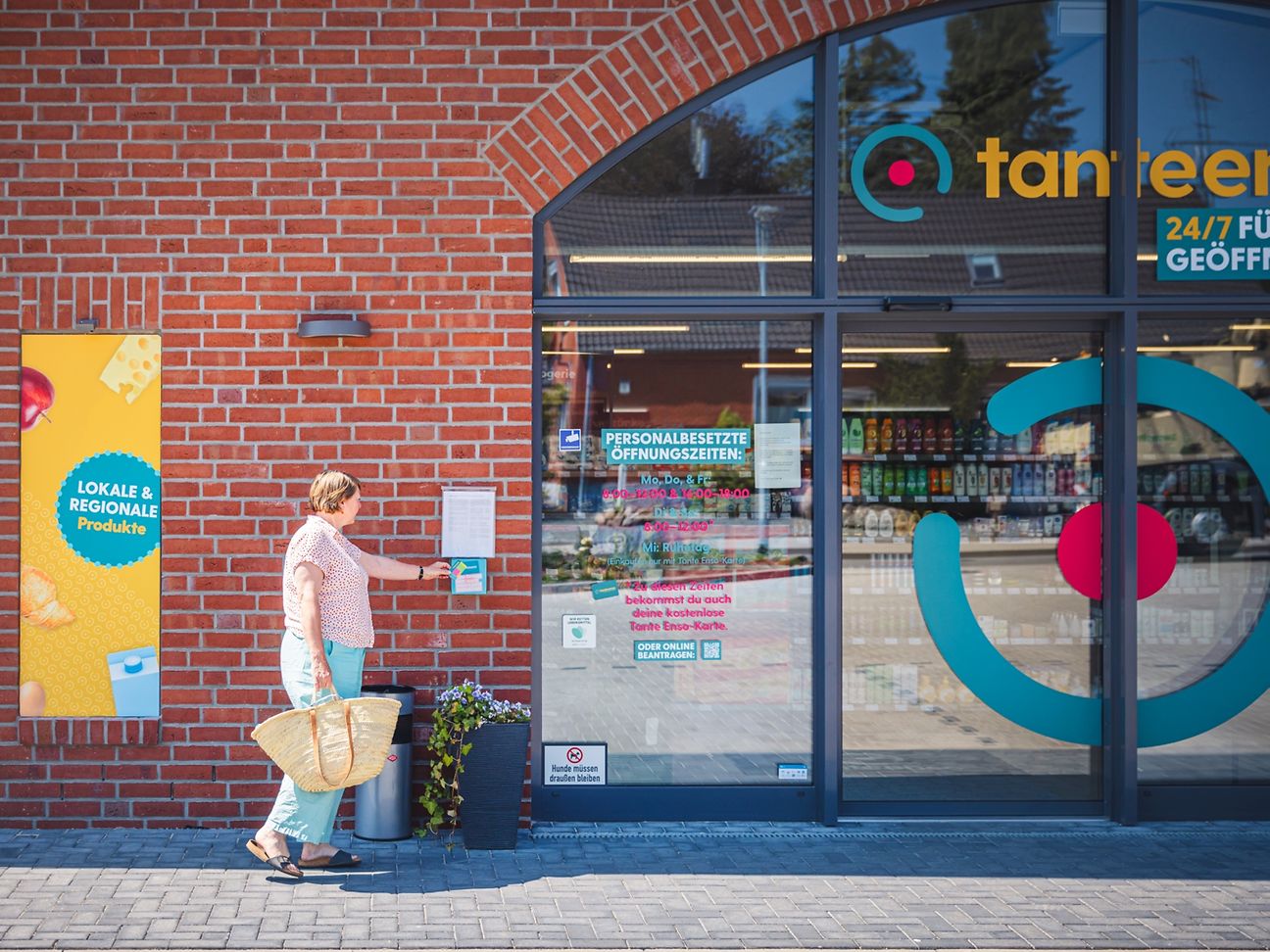 Woman with shopping bag opens supermarket door with access card.