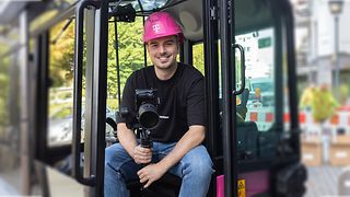 Nick Schneider (Corporate Communications Trainee) sits in the cockpit of a Magenta excavator with his camera equipment.