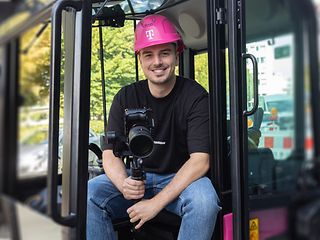 Nick Schneider (Corporate Communications Trainee) sits in the cockpit of a Magenta excavator with his camera equipment.