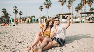 Paar mit Smartphone am Strand