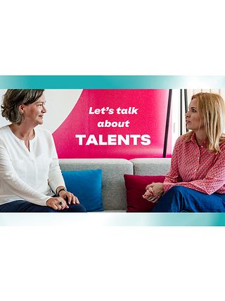 Bild von zwei Managerinnen, die auf einem Sofa sitzen und diskutieren.