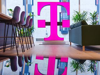 Das großes magenta Logo der Telekom vor einem Fenster