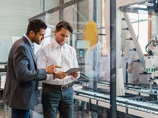 Two male employees looking at a tablet.