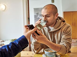 Ein Mann schaut während des Frühstücks auf ein Handy.