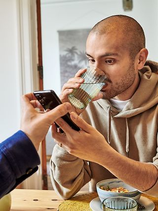 Ein Mann schaut während des Frühstücks auf ein Handy.