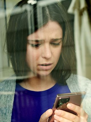 Pensive young woman looking at her smartphone.