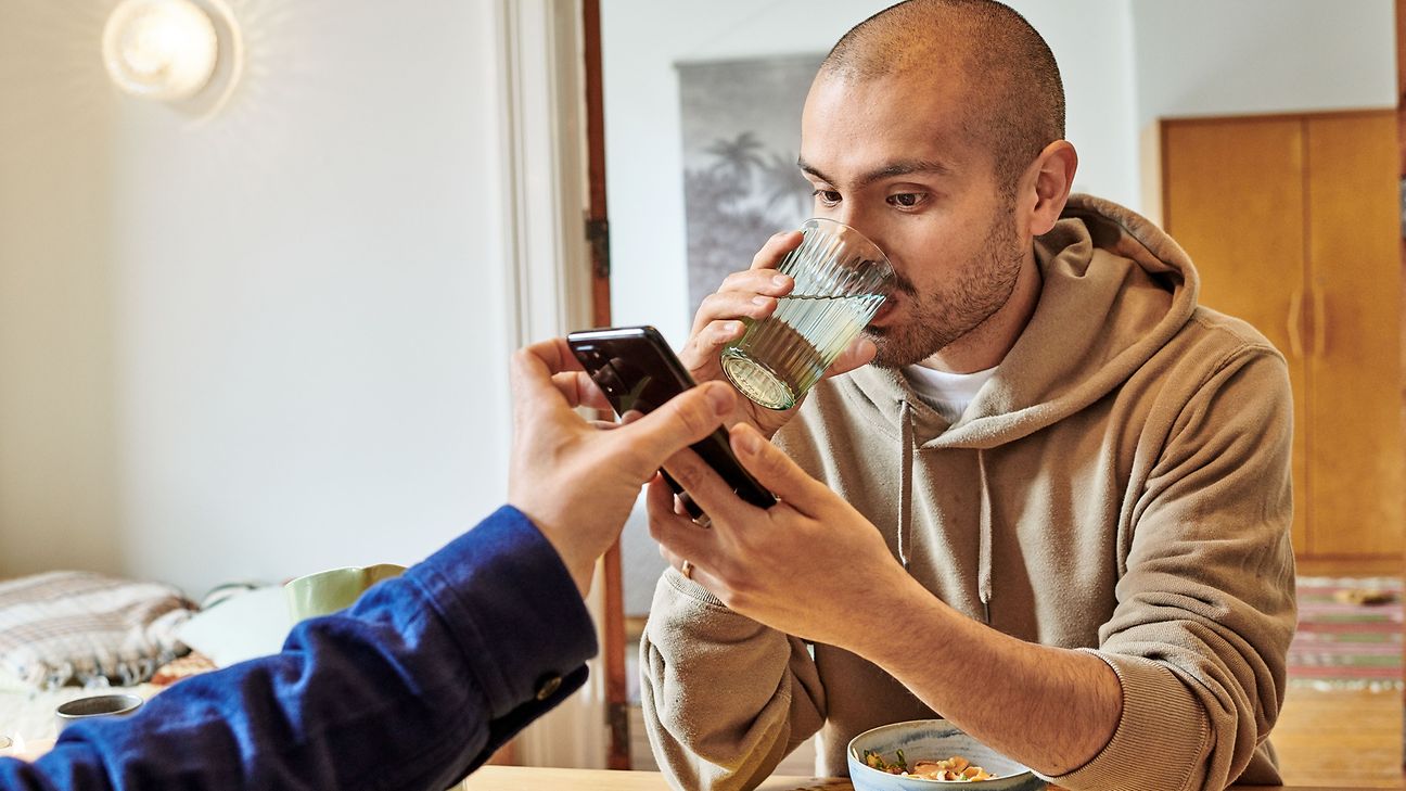 A man takes a look at a mobile phone while having breakfast.