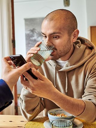 A man takes a look at a mobile phone while having breakfast.