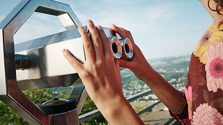 A woman on a hill view point with binoculars.