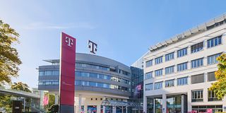 Außenansicht der Telekom Zentrale in Bonn mit magenta-farbenen Fahnen vor dem Eingangsbereich und dem T-Logo auf dem Dach