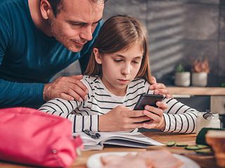 Vater mit Tochter schauen auf ein Handy