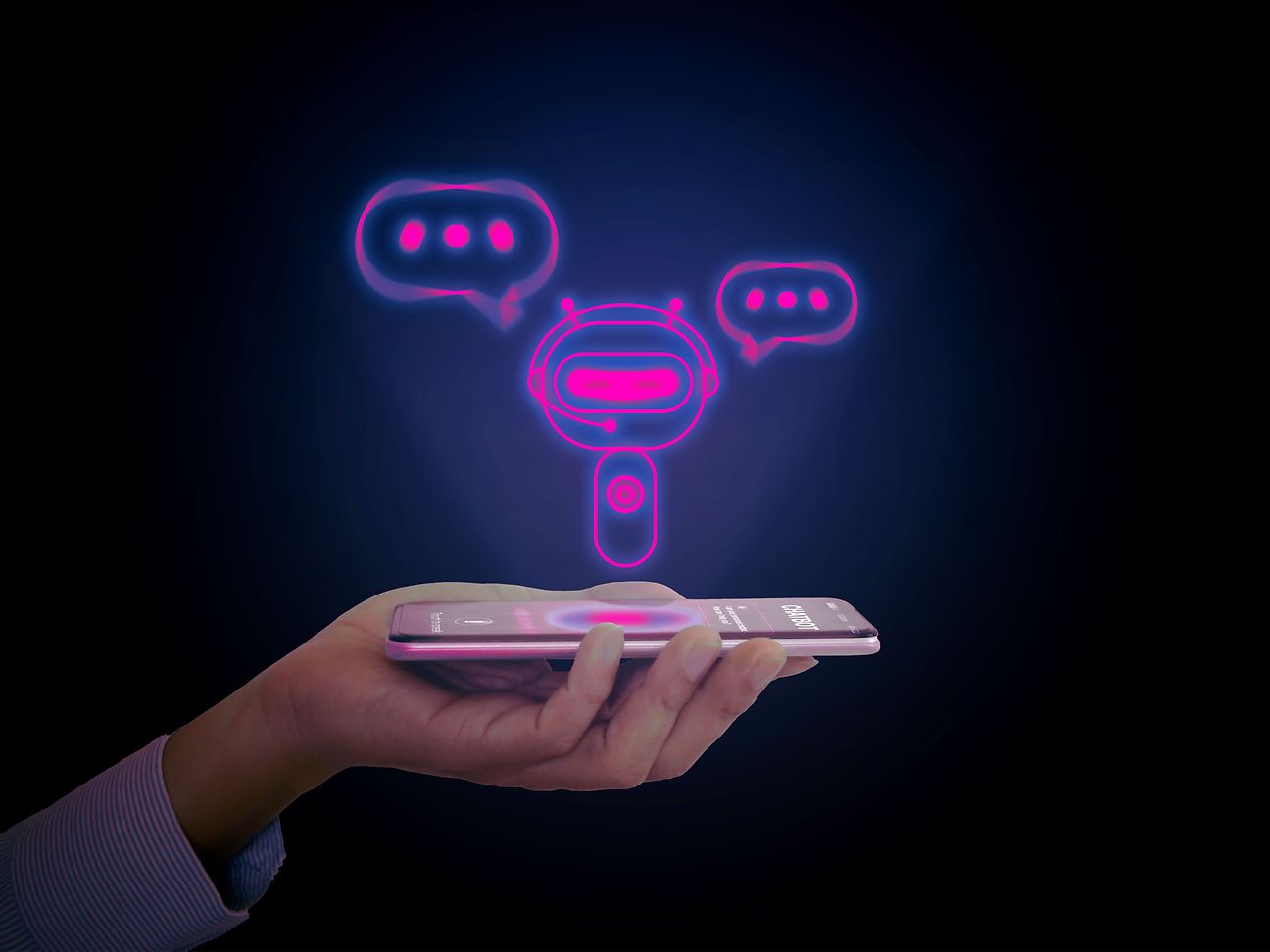 Hand holds smartphone. A small robot with a headset and speech bubbles around its head hovers above the display.
