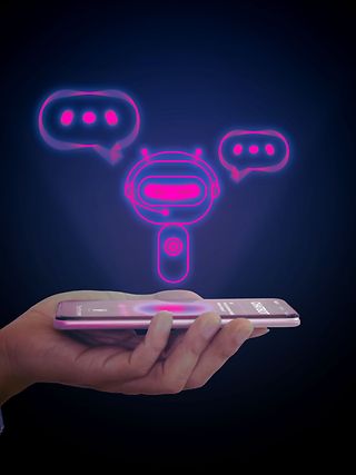 Hand holds smartphone. A small robot with a headset and speech bubbles around its head hovers above the display.