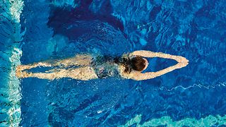 Eine Person schwimmt in einem Schwimmbecken, gesehen von oben