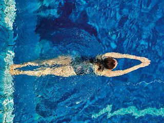 Eine Person schwimmt in einem Schwimmbecken, gesehen von oben