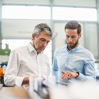 Zwei Männer in einem modernen Büro mit Blick auf ein Tablet 