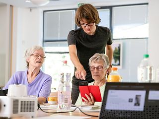 The picture shows how older people are trained in the use of digital devices.