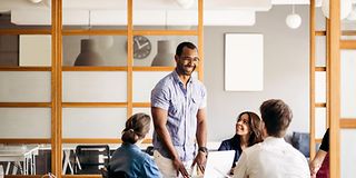 Smiling man talking to colleagues in a modern office