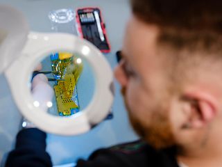  A man working on a micro-chip looking through a magnifying glass