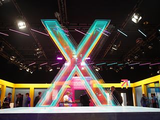 Colorful, glowing X in front of a dark background.