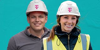 Man and woman wearing pink construction helmets with the Deutsche Telekom logo and smiling into the camera