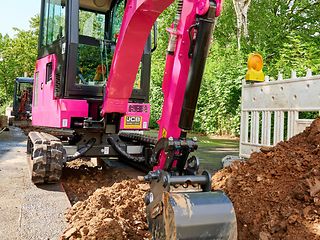 magenta farbener Bagger bei Tiefbauarbeiten