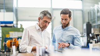 Two men in a modern office looking at a tablet