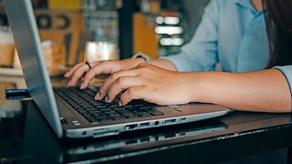 Hands typing on the keyboard of a laptop.