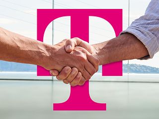 Two hands shaking in front of a large magenta Deutsche Telekom logo