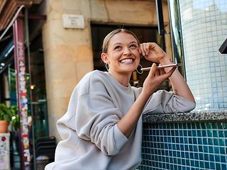 A young woman is talking into her smartphone and smiling happily