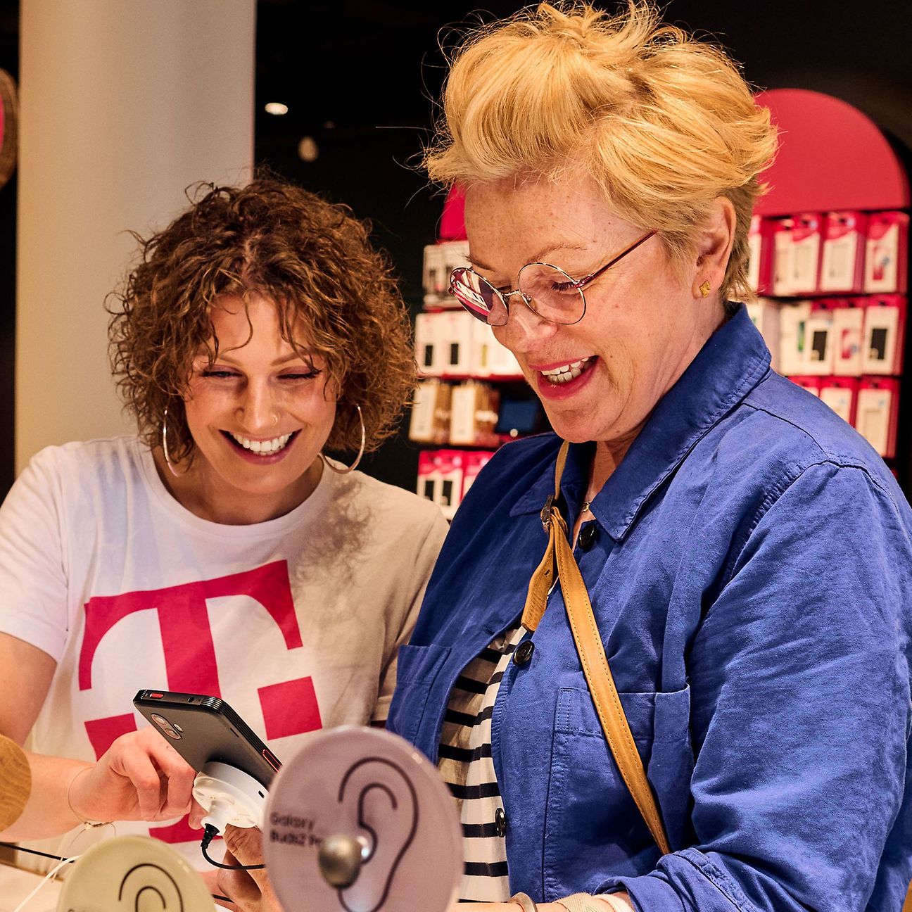 An employee of the Telekom Shop advises a customer and shows her something on her smartphone