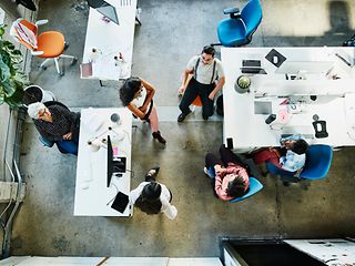 Several employees standing and sitting together in the office. View from above.