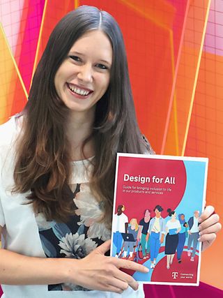 Annika Theiß holds the „Design for All Guide“ in her hands.