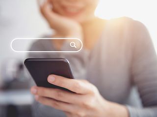 Woman holding smartphone. Search field seen above.