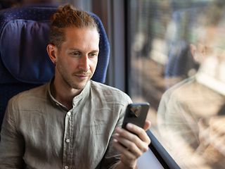 Mann sitzt im Zug am Fenster