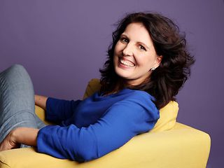  A woman sits on an armchair and smiles at the camera