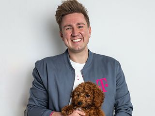  A young man holds a dog and smiles at the camera